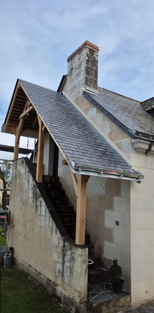 Détail d'un auvent d'escalier couvert en ardoise sur une façade en tuffeau
