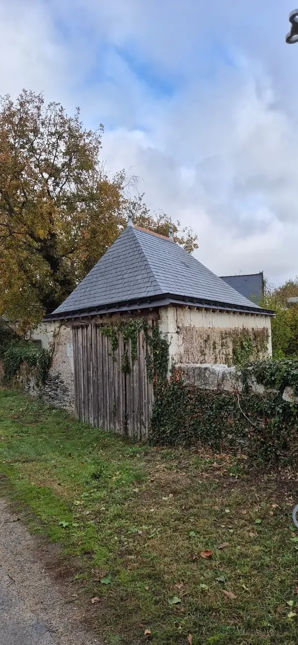 Petit bâtiment à quatre pans recouvert d'ardoise neuve au fond d'un jardin