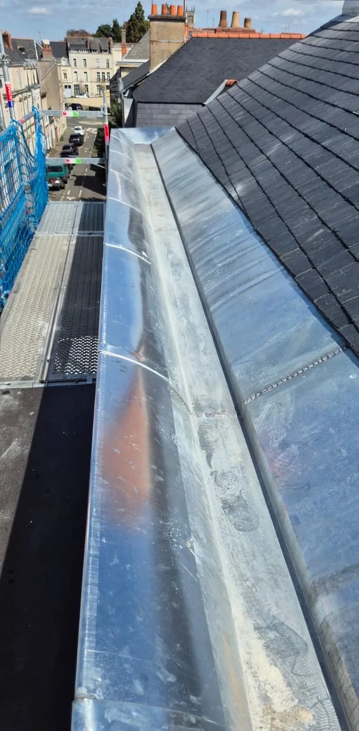 Chéneau en zinc neuf le long d'un versant en ardoise