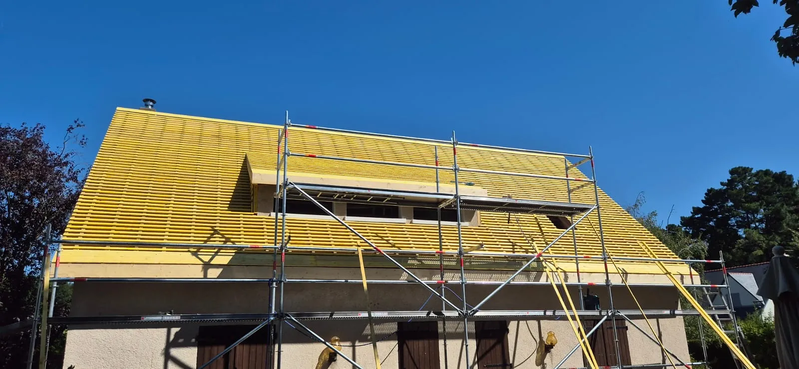 Réfection de toiture en cours : écran sous toiture et liteaux posés, échafaudage sur toute la façade